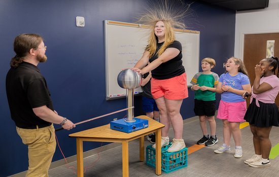 educator demonstration static electricity to a group of guests.jpg