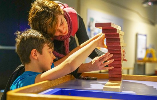 Family builds wooden block stack in the Science Unplugged exhibition