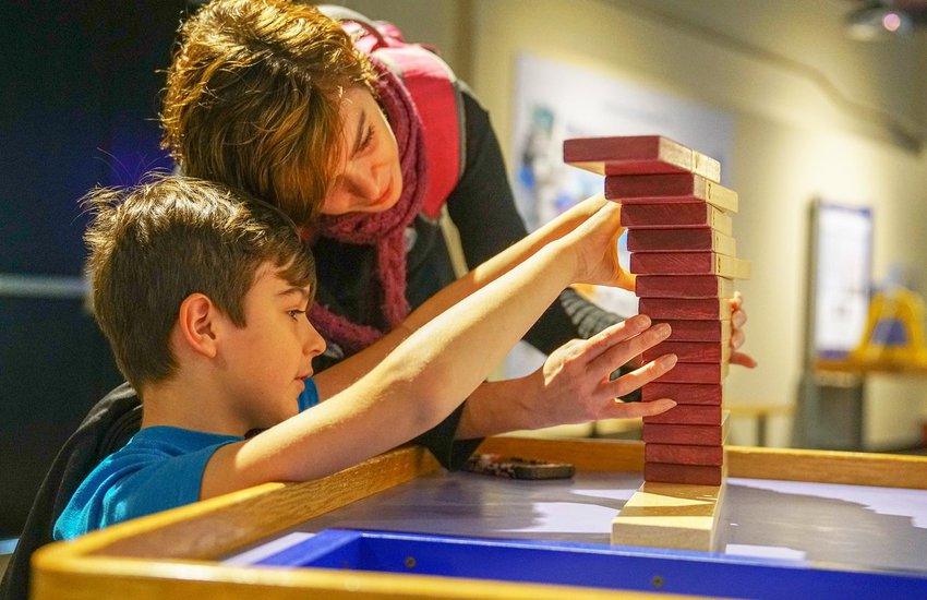 Family builds wooden block stack in the Science Unplugged exhibition