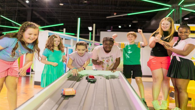 diverse group of young guests engaging with car racing exhibit in Go.jpg